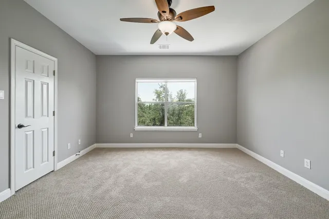 a view of a white house next to a yard with big trees