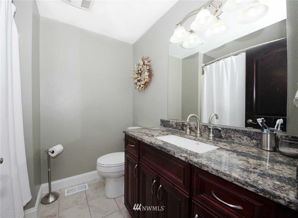 18131 Case Road Southwest Rochester, WA 98579 - Photo 11 of 16 a bathroom with a granite countertop sink a toilet and a mirror