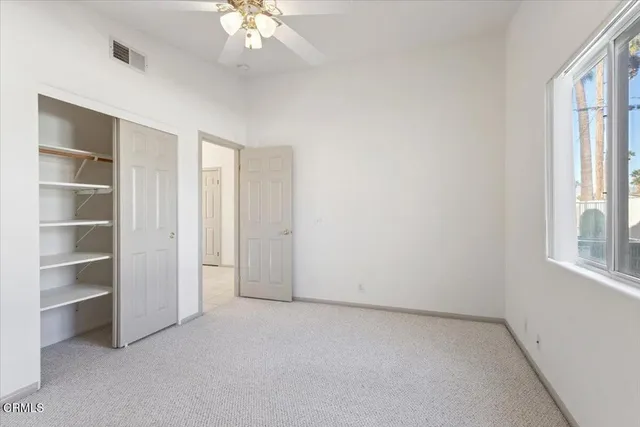 an empty room with a chandelier fan and closet