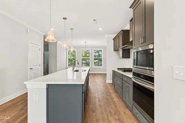 a center kitchen with stainless steel appliances kitchen island granite countertop a stove top oven a sink and dishwasher