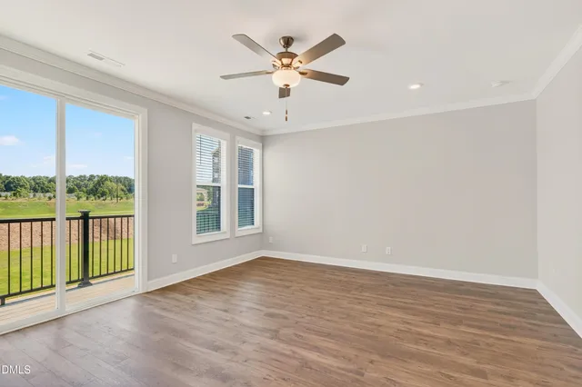 an empty room with wooden floor fan and windows