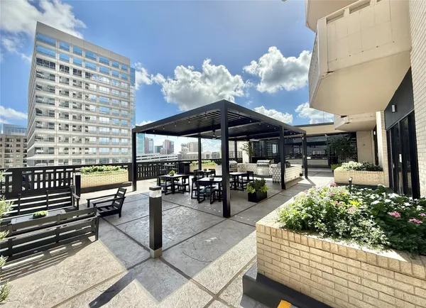 a view of a patio with dining table and chairs under an umbrella with a barbeque grill and couches