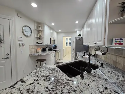 a kitchen with granite countertop a sink and a stove top oven