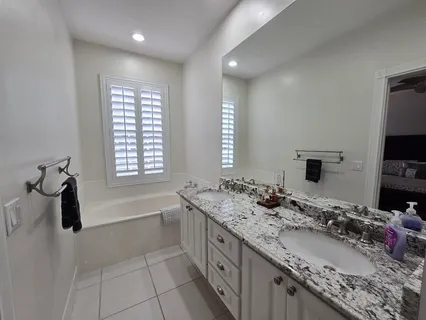 a bathroom with a granite countertop sink a toilet a mirror and shower