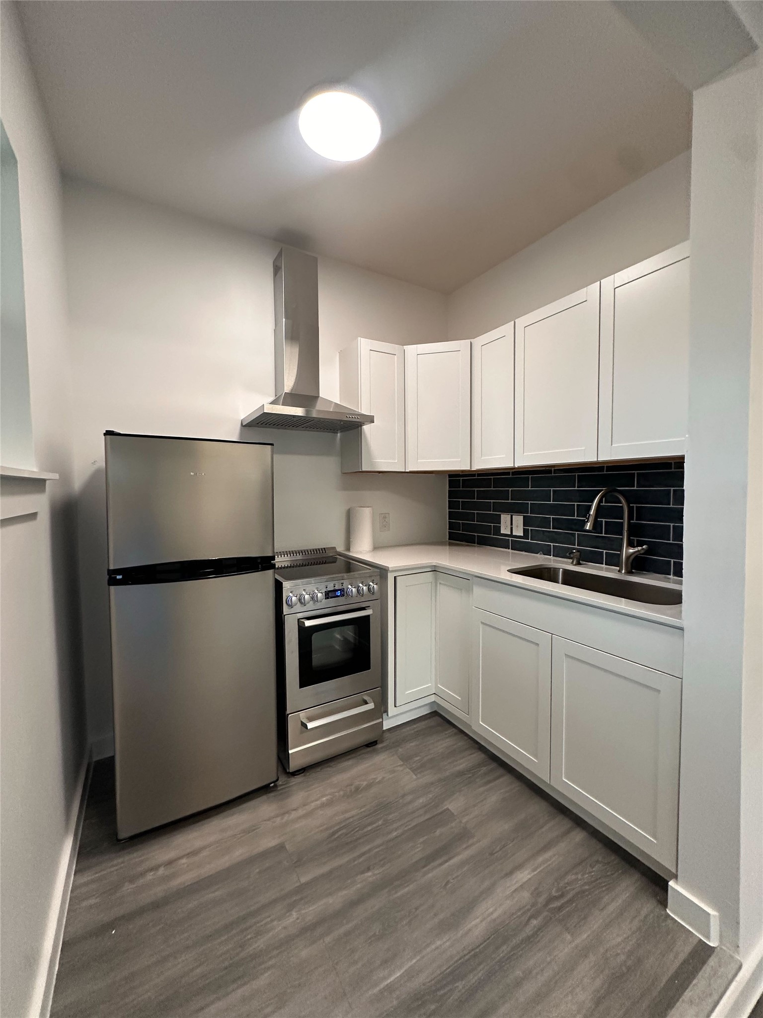 1302 Ridgecrest Drive Austin, TX 78746 - Photo 8 of 19 Crisp white cabinetry and modern stainless steel appliances define this streamlined kitchen space.