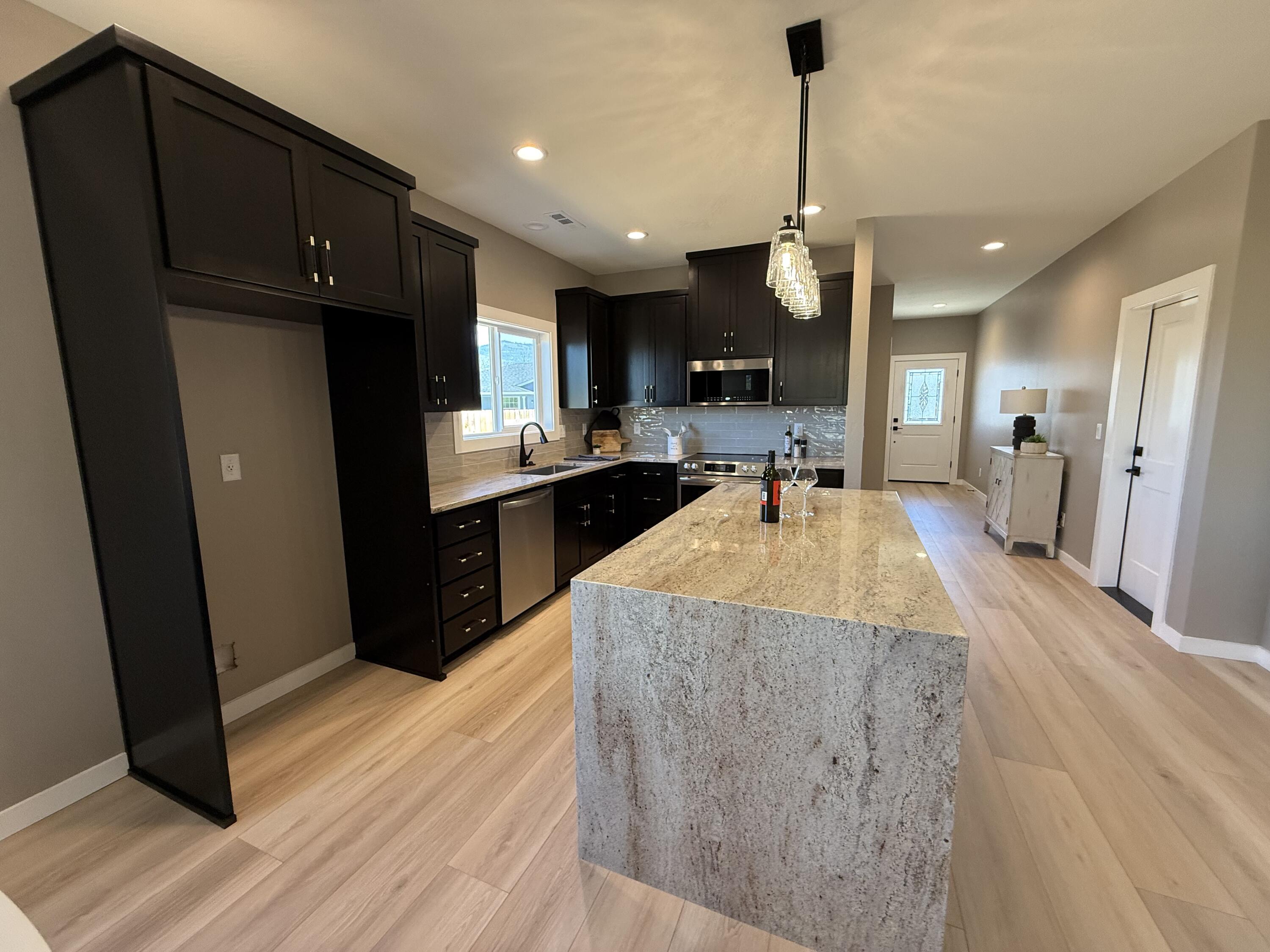 337 Quail Circle Talent, OR 97540 - Photo 5 of 25 a kitchen with kitchen island granite countertop wooden cabinets a refrigerator a sink a stove and wooden floor