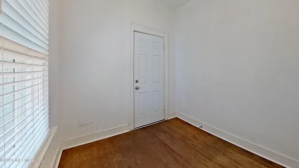 a view of a small space with wooden floor and a window
