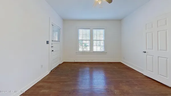 an empty room with wooden floor and windows