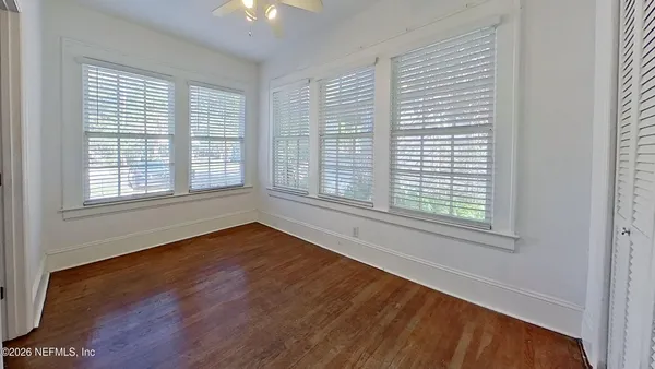 a view of an empty room with wooden floor and a window