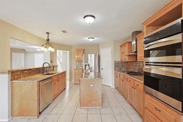 a large kitchen with stainless steel appliances granite countertop a stove and a sink