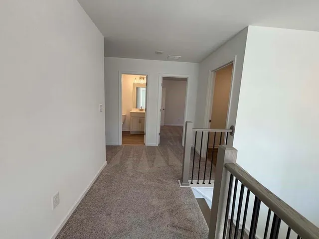 a view of a hallway with wooden floor and a bathroom