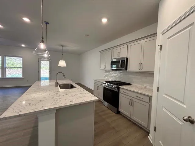 a kitchen with stainless steel appliances granite countertop a sink a stove and a wooden floors