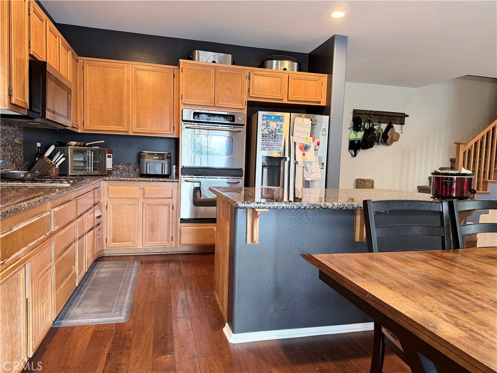 562 Quigley Lane Perris, CA 92570 - Photo 8 of 29 a kitchen with stainless steel appliances wooden floors and wooden cabinets