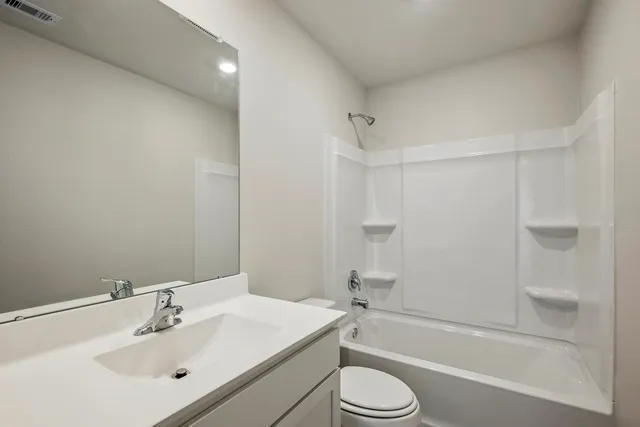 a bathroom with a bathtub shower sink vanity mirror and toilet