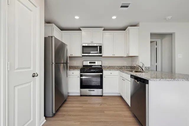 a kitchen with granite countertop a refrigerator and a stove top oven