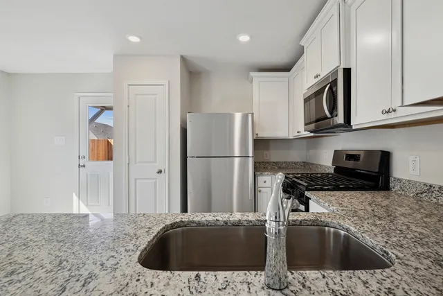 a kitchen with stainless steel appliances granite countertop a sink a stove and a refrigerator