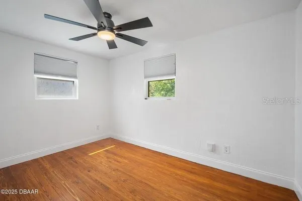 an empty room with wooden floor and windows