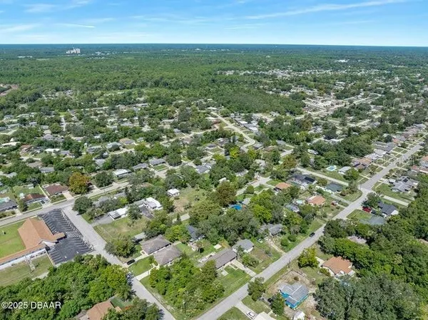 an aerial view of residential houses with outdoor space and trees