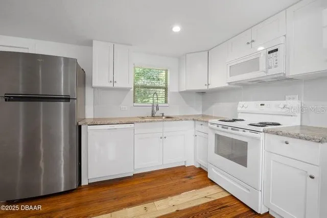 a kitchen with white cabinets and white appliances
