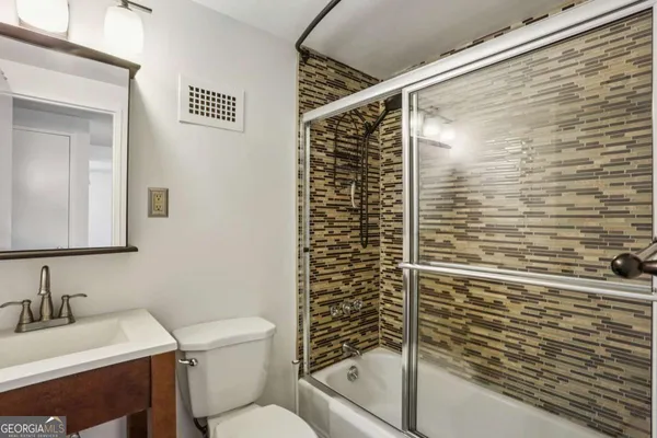 a bathroom with a granite countertop sink toilet and shower