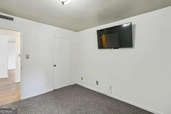 a view of an empty room with wooden floor and a flat screen tv