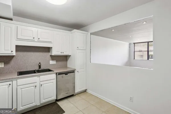 a kitchen with white cabinets and sink