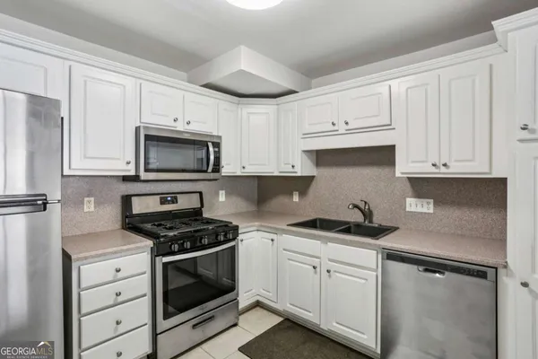 a kitchen with white cabinets and appliances