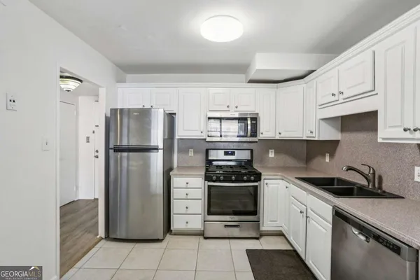 a kitchen with stainless steel appliances a refrigerator stove and white cabinets