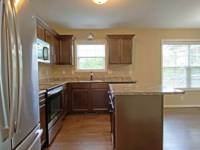 a kitchen with granite countertop a sink stove and refrigerator