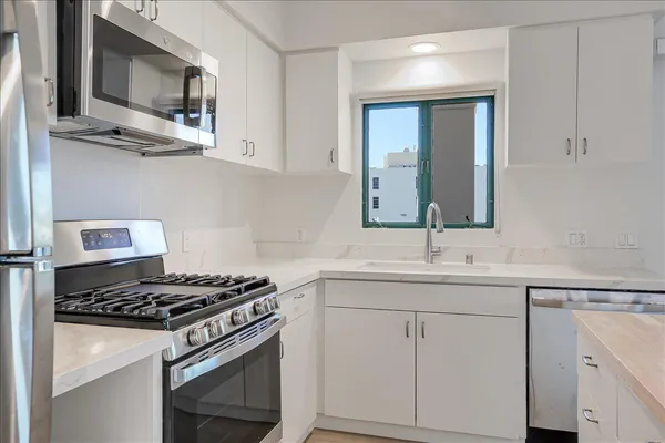 a kitchen with stainless steel appliances white cabinets and a stove top oven