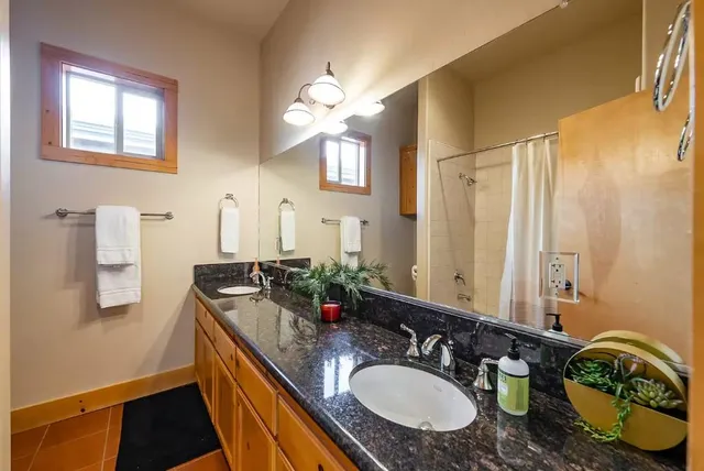 a bathroom with a granite countertop double vanity sink and a mirror