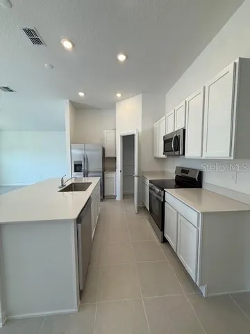 a large kitchen with stainless steel appliances a sink a stove and cabinets