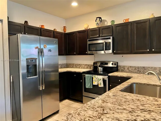 a kitchen with granite countertop a refrigerator and a stove top oven