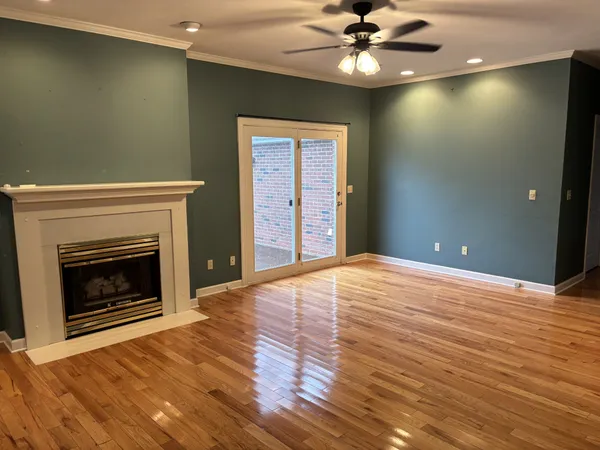 a view of an empty room with wooden floor a fireplace and a window