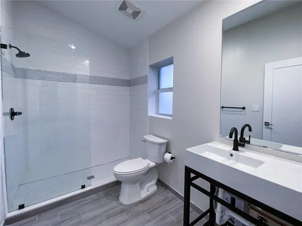 a bathroom with a sink a toilet and shower