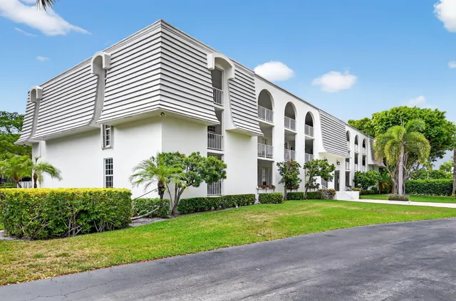 a view of a white house with a yard and plants