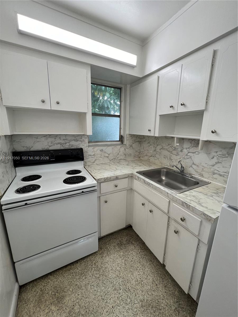 675 Southwest 7th Avenue, Unit 12 Miami, FL 33130 - Photo 4 of 13 a kitchen with granite countertop white cabinets and white appliances