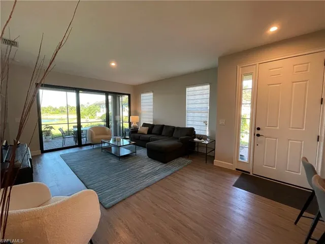 a living room with furniture a wooden floor and a large window