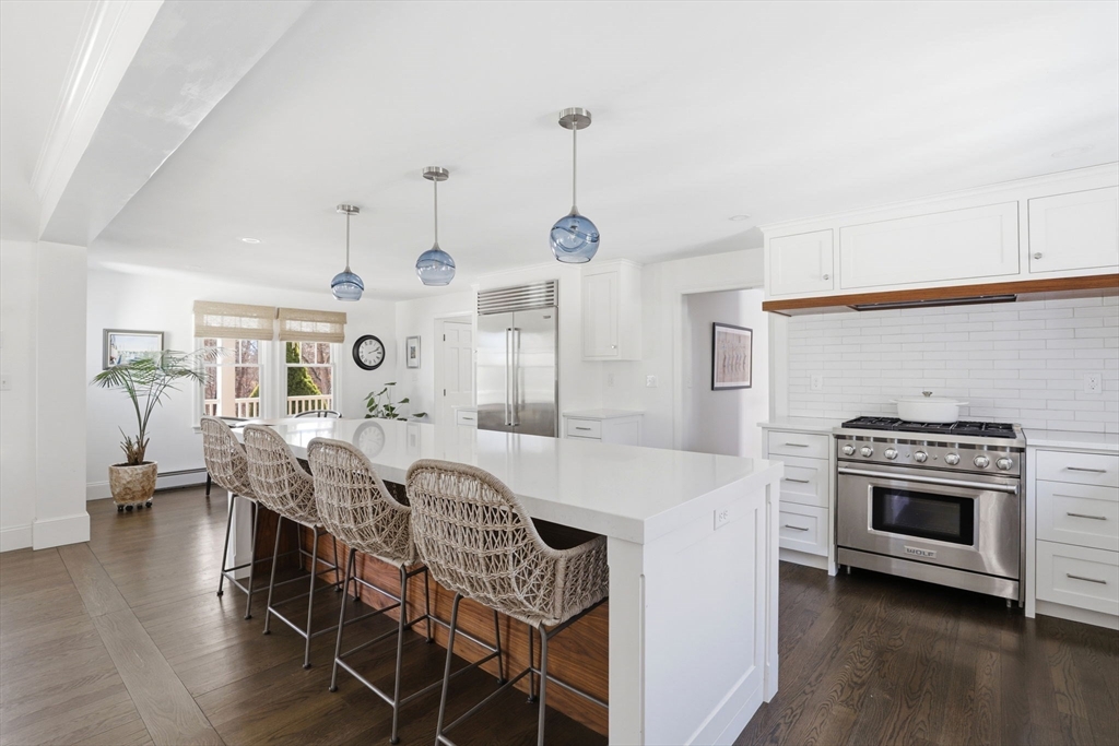 24 Ridge Hill Road Scituate, MA 02066 - Photo 9 of 38 a open kitchen with stainless steel appliances granite countertop a stove top oven a sink a dining table and chairs with wooden floor