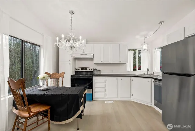 a kitchen with stainless steel appliances granite countertop a stove top oven a refrigerator a sink and a dining table with garden view