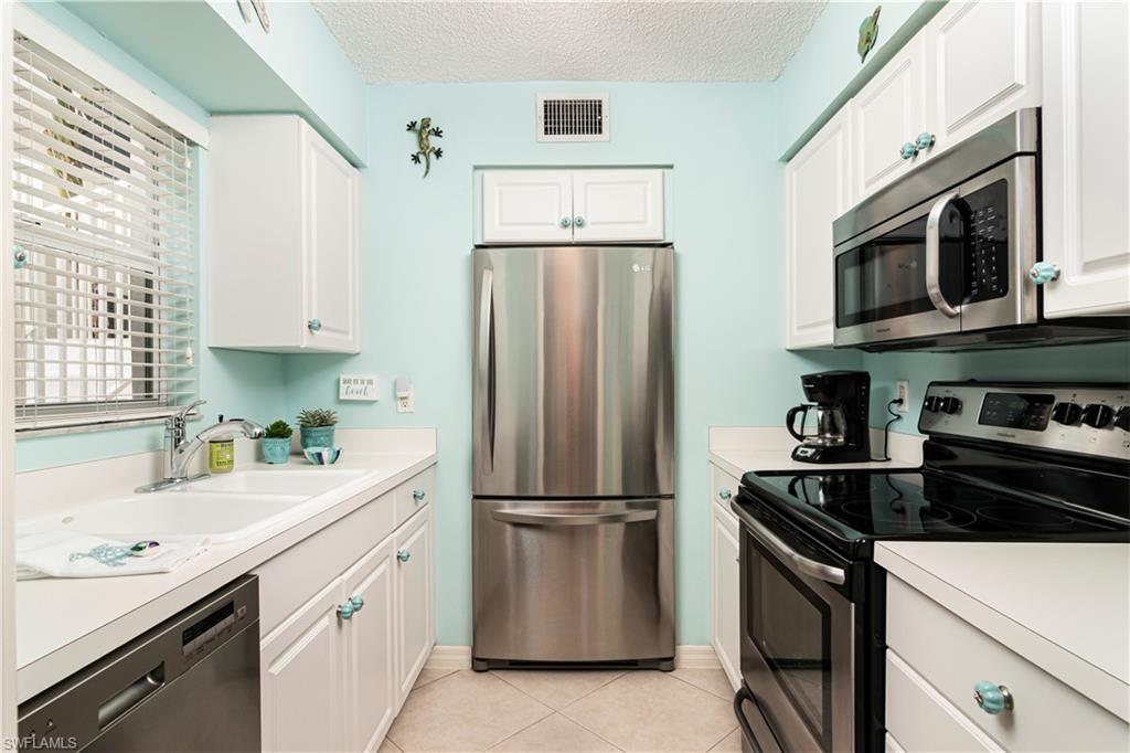 284 4th Street South, Unit 103 Naples, FL 34102 - Photo 6 of 11 a kitchen with stainless steel appliances a refrigerator sink and microwave