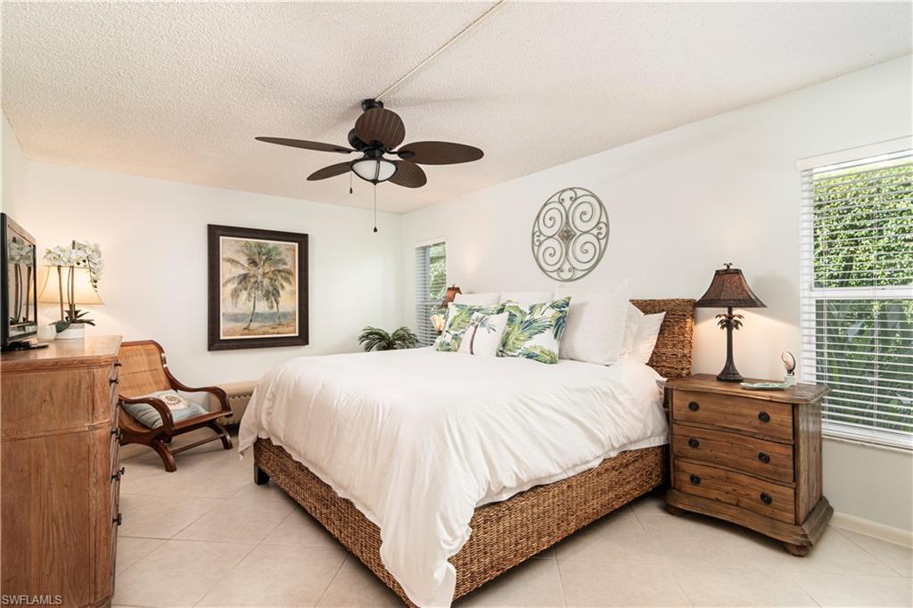 284 4th Street South, Unit 103 Naples, FL 34102 - Photo 7 of 11 a bedroom with a bed and a chandelier