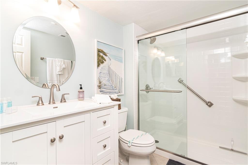 284 4th Street South, Unit 103 Naples, FL 34102 - Photo 8 of 11 a bathroom with a shower sink vanity mirror and toilet