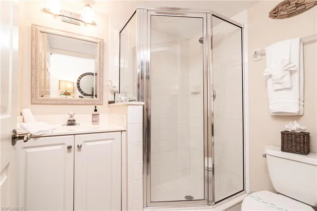 a bathroom with a shower sink and mirror with toilet