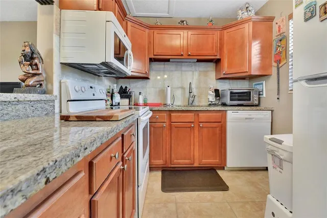 a kitchen with stainless steel appliances granite countertop a sink a stove and a wooden cabinets