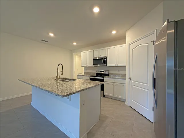a kitchen that has a refrigerator a sink and cabinets