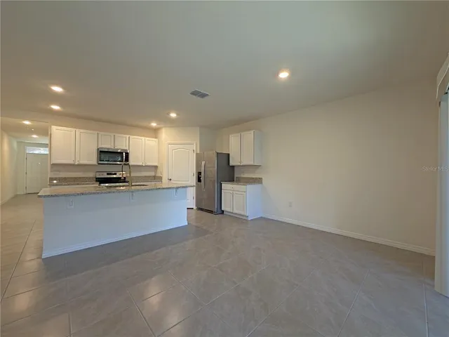 a view of kitchen with kitchen island sink stainless steel appliances and cabinets