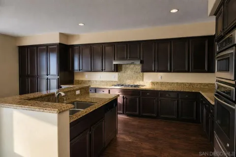 a kitchen with granite countertop stainless steel appliances a stove sink and cabinets