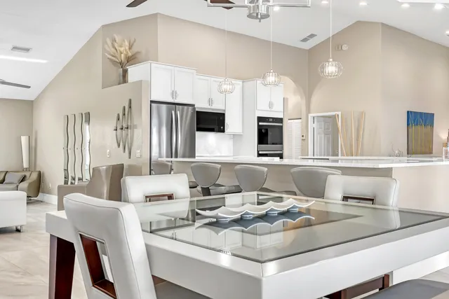 a large white kitchen with stainless steel appliances kitchen island a table and chairs