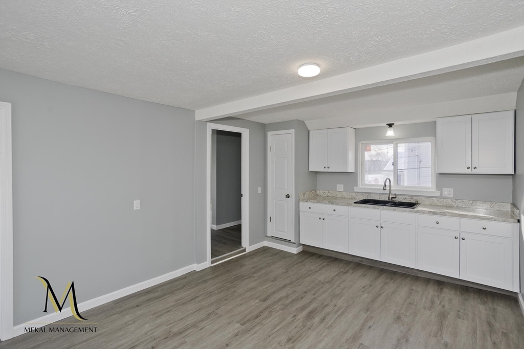 131 Center Street, Unit 131 Holyoke, MA 01040 - Photo 2 of 12 a large kitchen with a wooden floor and white stainless steel appliances